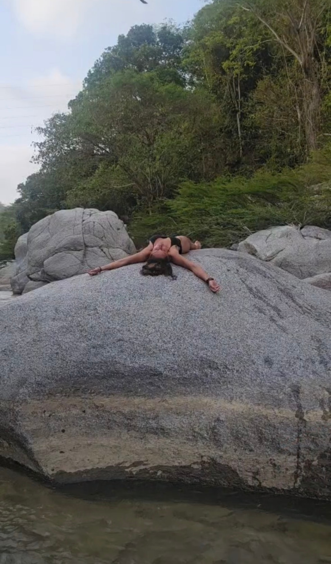 Melissa Sapmaz tumbada sobre una roca junto al río